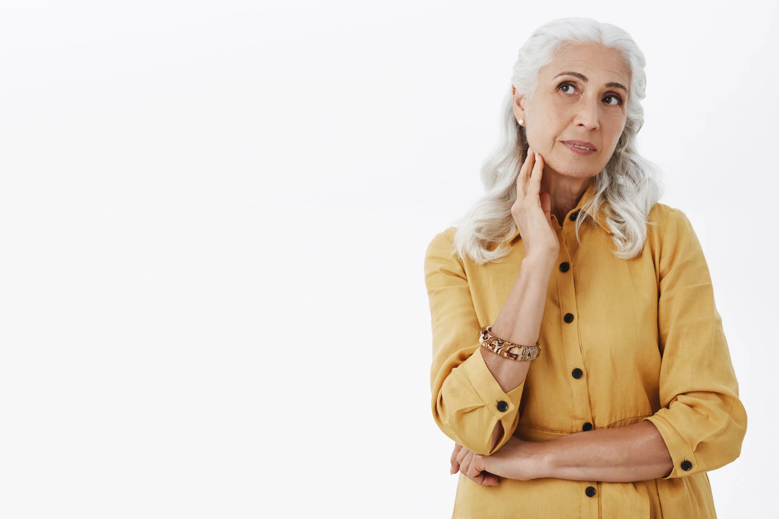Waist Up Shot Of Beautiful Stylish And Elegant Senior Female In Trendy Yellow Trench Coat And Bracelet Touching Neck Gently Gazing Feminine Aside As If Dreaming Feeling Confident In Own Beauty